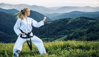 Young girl with a black belt performing martial arts in the mountains