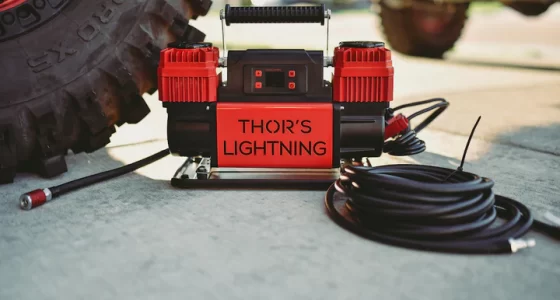 Thor's Lightning Adventure Gear air compressor on ground next to big vehicle tyre